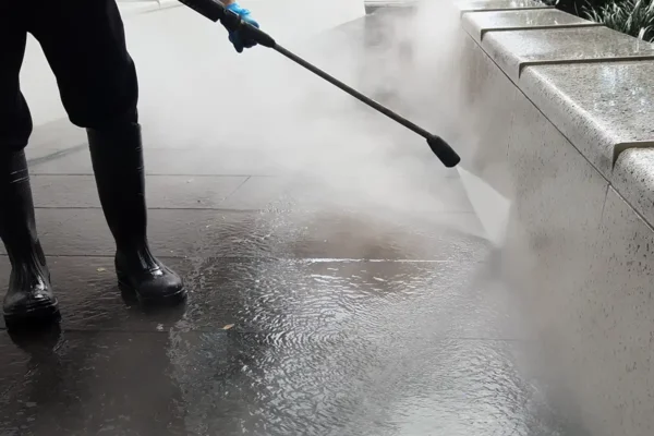 Man using pressure washing equipment on exterior stone surface